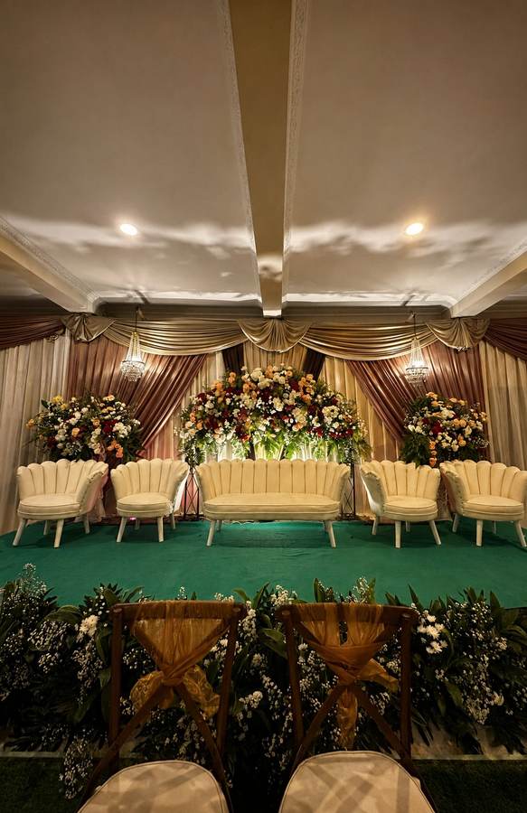 Pelaminan modern dengan drapery keemasan dan rangkaian bunga besar