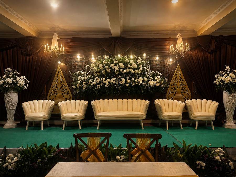 Pelaminan dengan lampu gantung kristal dan rangkaian bunga putih