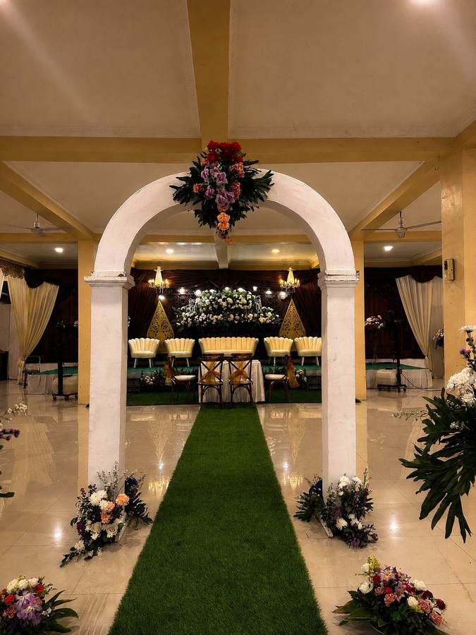 Lengkung pilar putih membingkai lorong hijau menuju pelaminan
