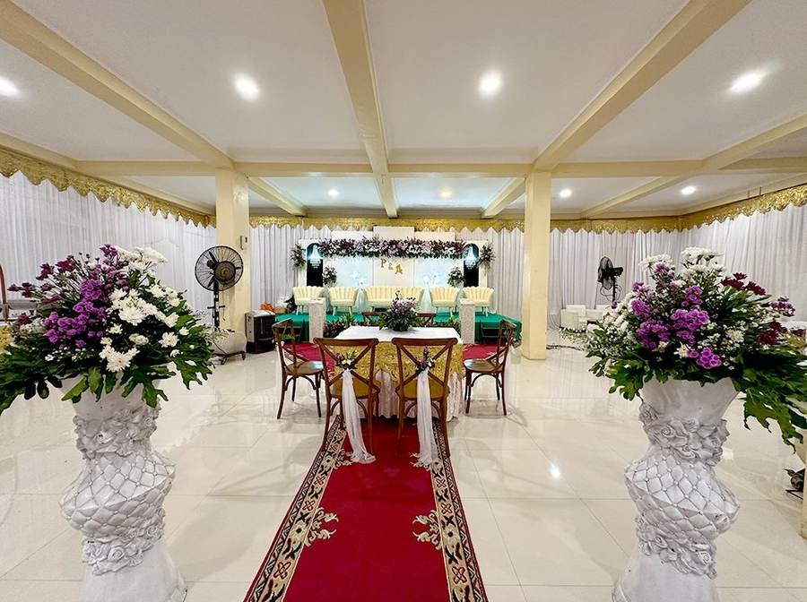 Lorong simetris dengan vas bunga besar di kedua sisi karpet
