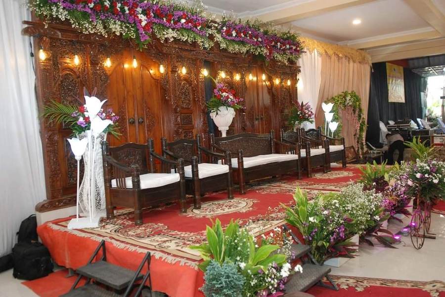 Pelaminan ukir kayu dengan standing flower di sepanjang panggung