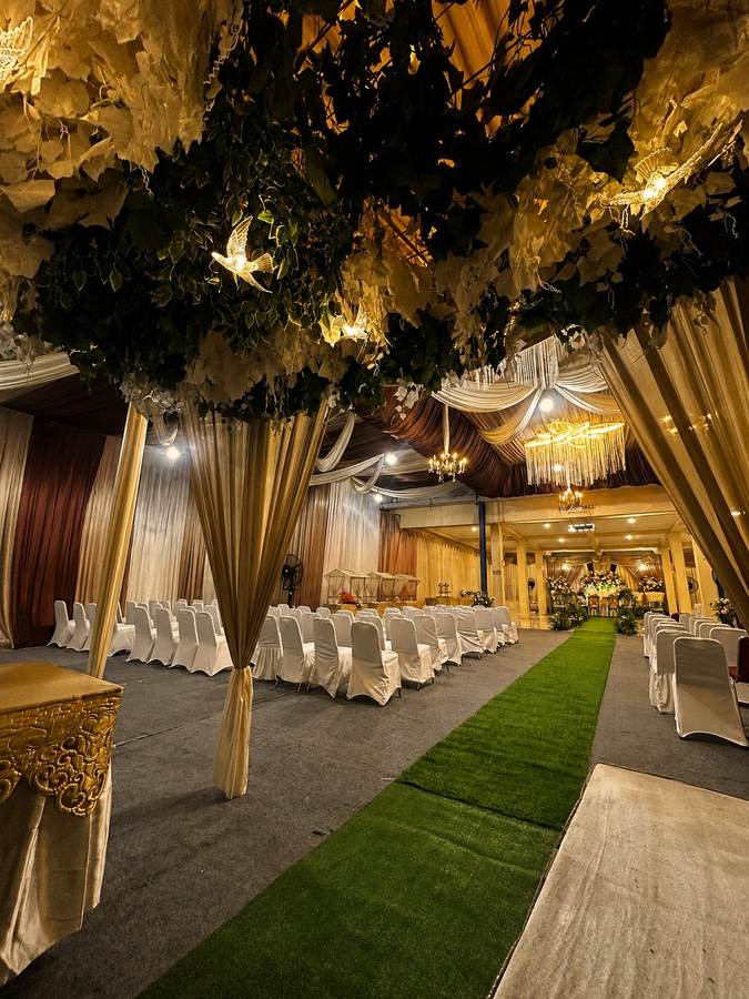 Drapery emas dan dedaunan menggantung membingkai lorong resepsi