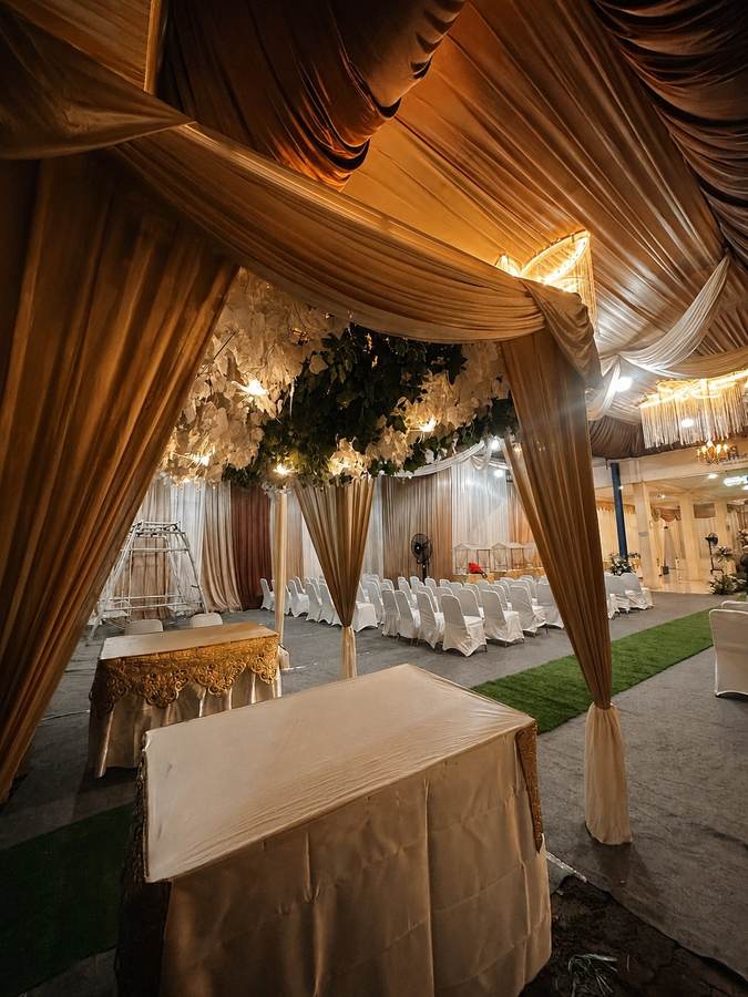 Dekorasi kain cokelat keemasan dengan ornamen bunga di area masuk