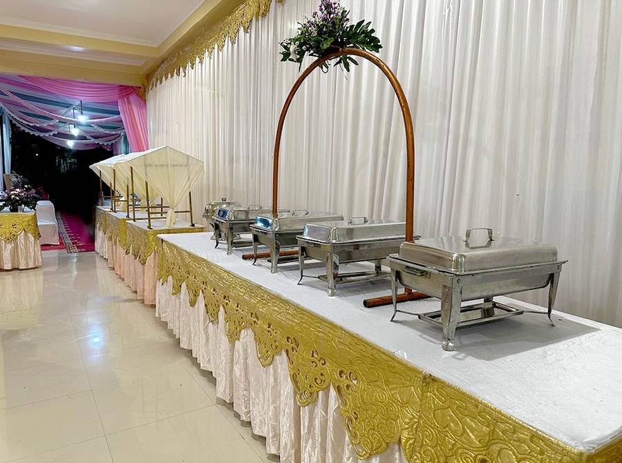 Meja buffet panjang dengan chafing dish dan dekorasi bunga