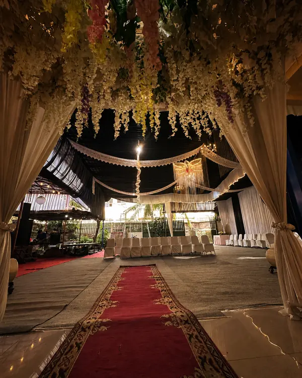 Dekorasi Gold & Black: tirai dan bunga gantung membingkai lorong karpet merah di area tenda